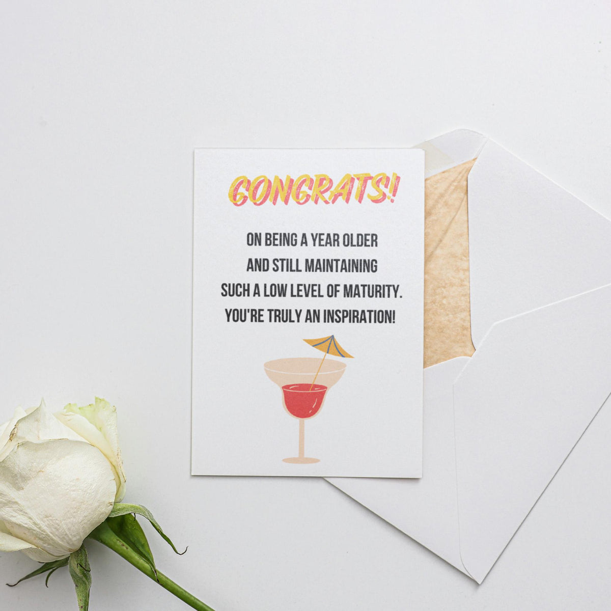 a white rose sitting next to two greeting cards