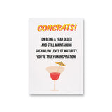 a card with a cocktail on it says congrats on being a year older