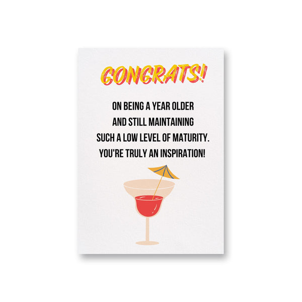 a card with a cocktail on it says congrats on being a year older