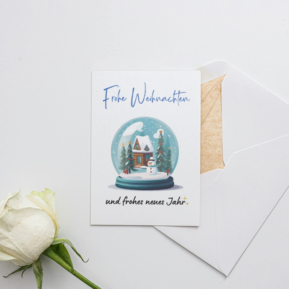 a card with a snow globe and a white rose